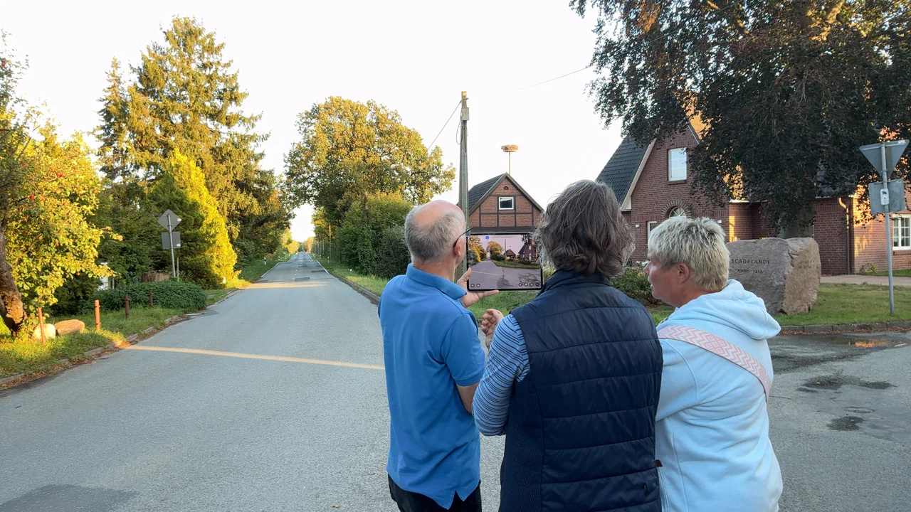 Teilnehmende betrachten auf einem Tablet geplante Windenergieanlagen in der realen Landschaft.